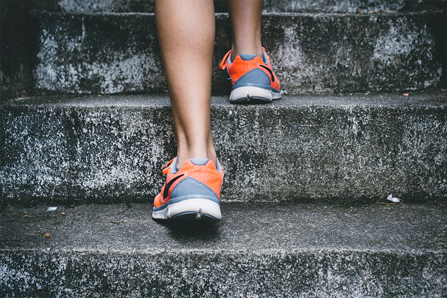pies con zapatillas deportivas suben una escalera