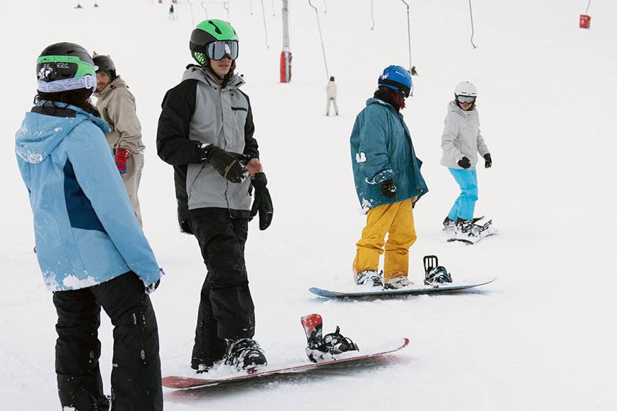 Estudiantes universitarios en la nieve montados sobre unos snowboards