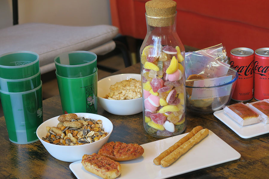 aperitivo de bienvenida para los estudiantes: patatas, frutos secos, tostadas, gominolas y coca cola en una mesa