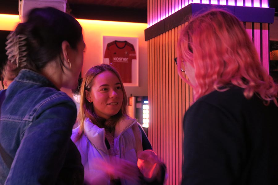 tres chicas universitarias hablan entre sí y se divierten en la fiesta de bienvenida de Cohousing en Pamplona
